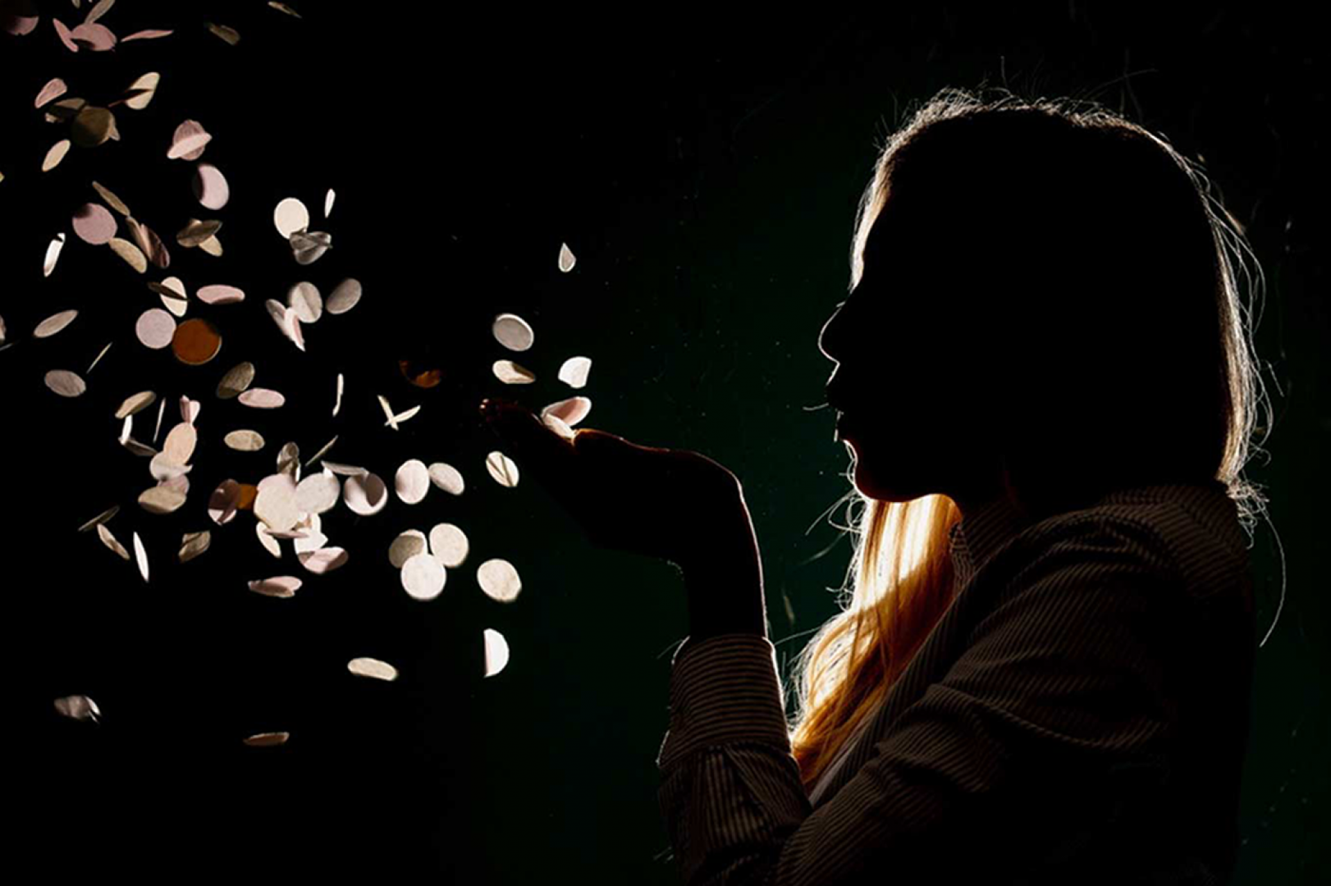 woman blowing confetti in the dark